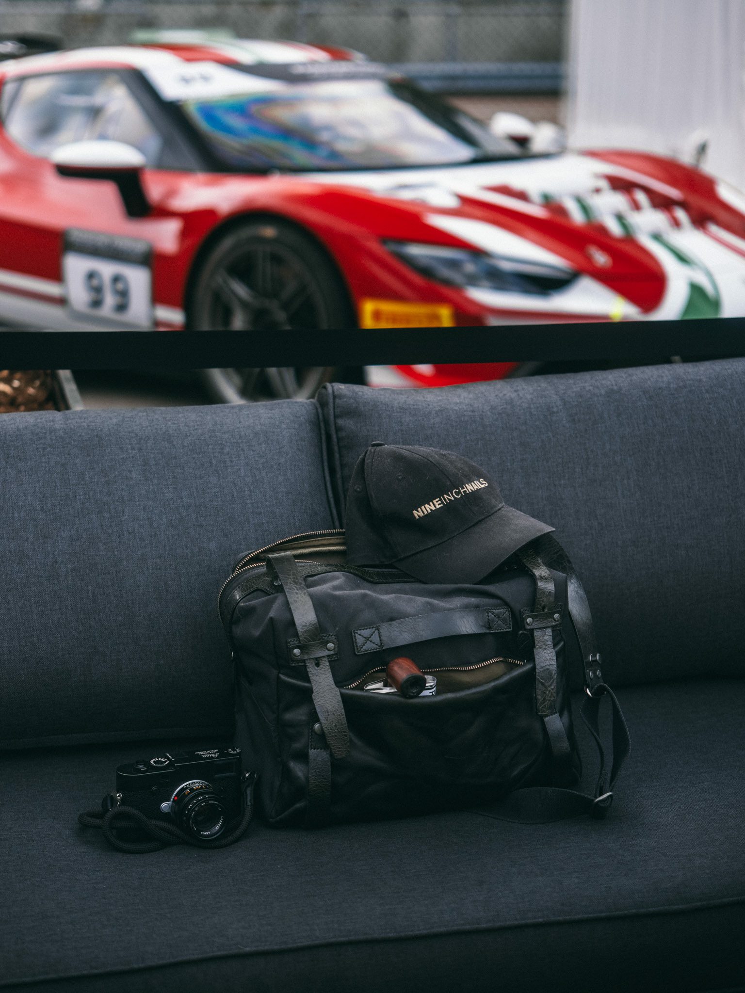 Camera bag, cap and camera on a grey sofa