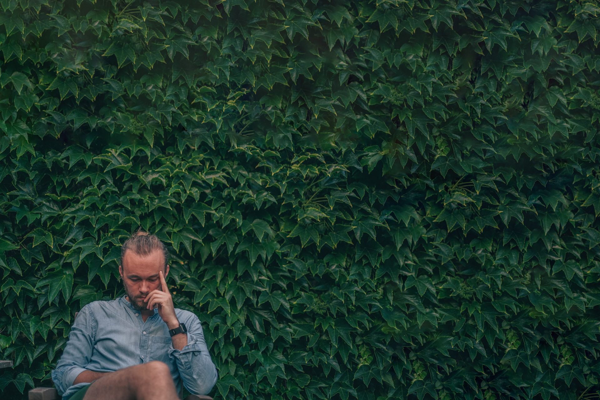 Rasmus sitting in front of an ivy-covered wall